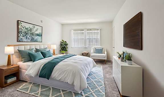 A bedroom with a large bed and a chair.