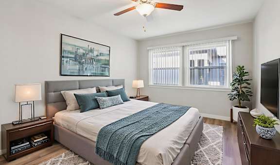A bedroom with a bed, a ceiling fan, and a window.