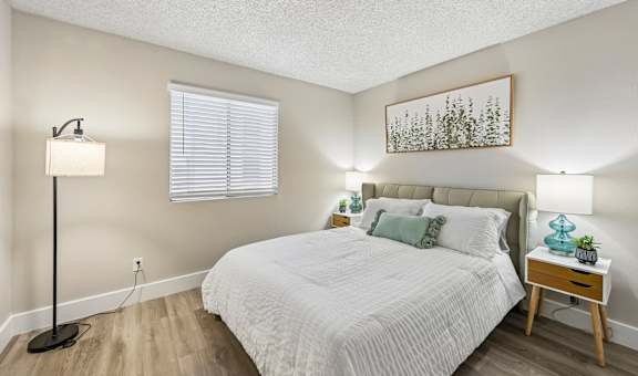 A bedroom with a bed, nightstand, and lamp.