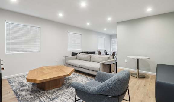 A modern living room with a grey sofa, a wooden coffee table, and a grey armchair.