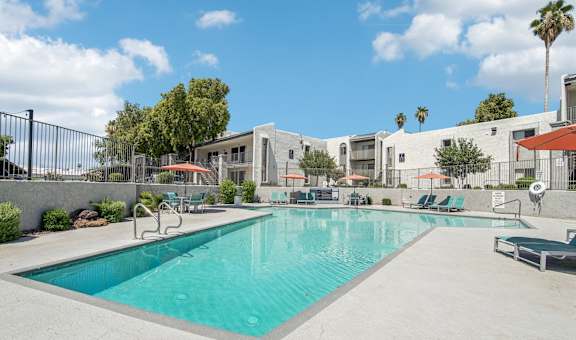 A large swimming pool in front of a building with a fence around it.