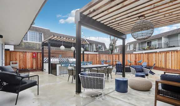 A patio with a black chair and a blue table.