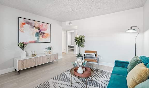 A living room with a green couch and a painting on the wall.