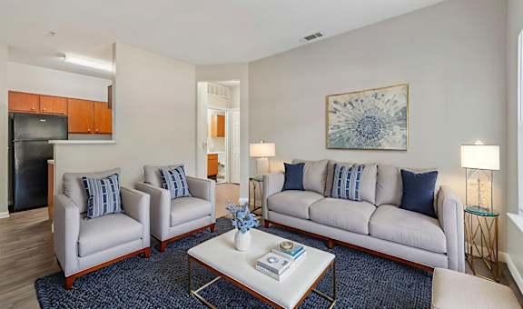 A living room with a grey couch, two armchairs, a coffee table, and a painting on the wall.