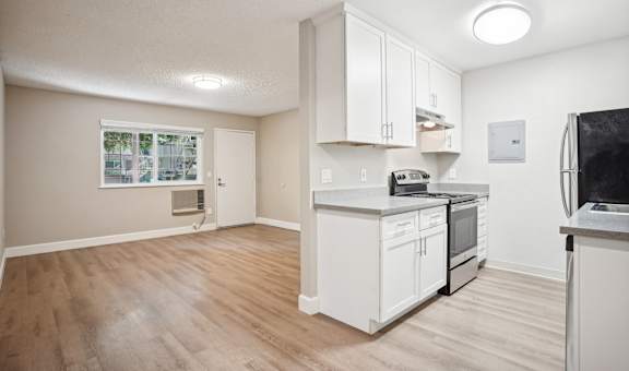 an empty kitchen and living room with white cabinets and appliances