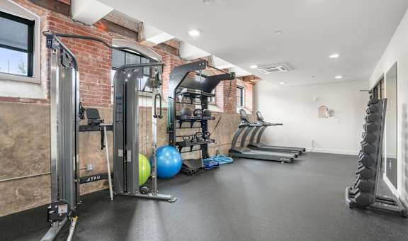 A gym with a variety of equipment including treadmills, exercise balls, and weights.