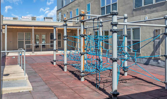 A playground with a blue climbing structure on a brick patio.