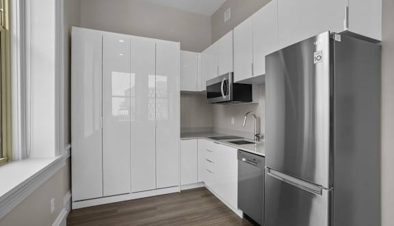 A kitchen with a refrigerator, microwave, and oven.