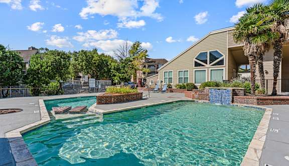 A large swimming pool with lounge chairs and a building in the background.
