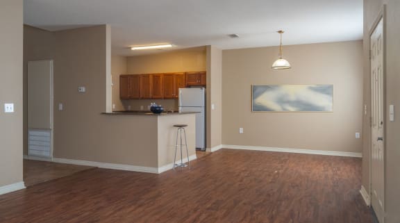an empty living room and kitchen with a wood floor