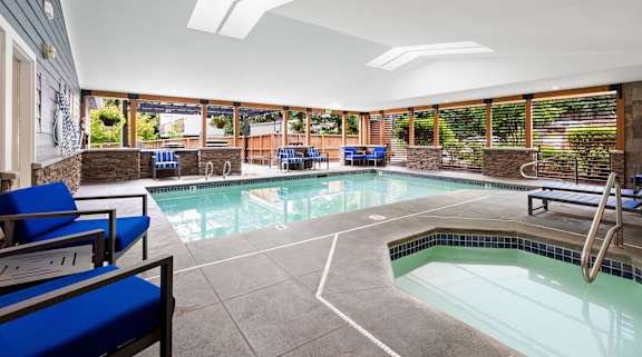 a swimming pool with blue chairs and a blue wall with a water feature