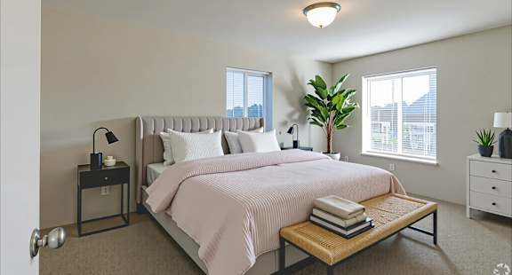 A bedroom with a large bed and a window with blinds.