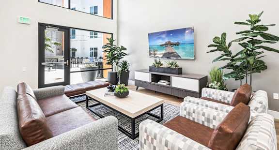 A living room with a brown leather couch, a white couch, a wooden coffee table, and a large painting on the wall.
