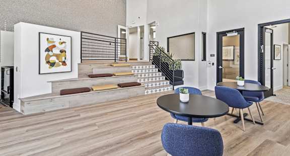 A modern living room with a staircase and a painting on the wall.