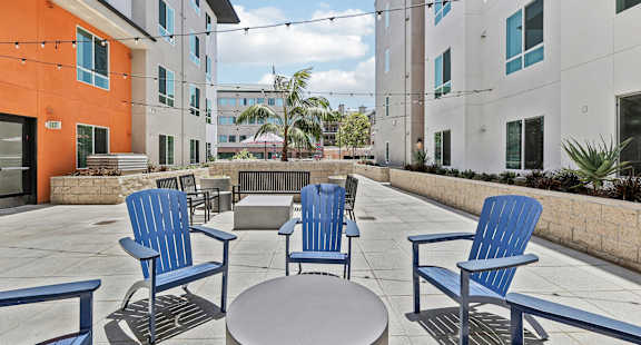 Four blue chairs and a table are on a patio.