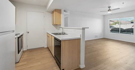 an empty kitchen and living room with wood flooring and a window