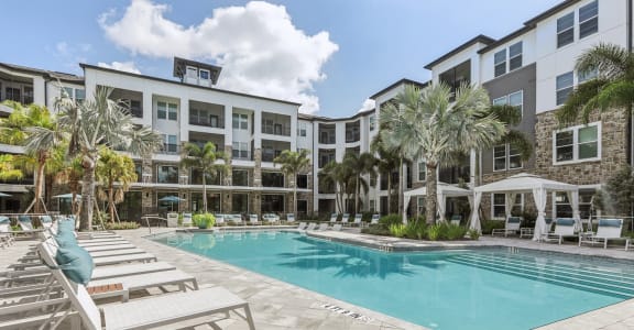 a swimming pool with lounge chairs and a building in the background