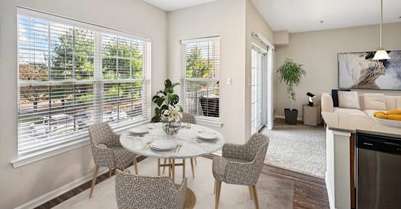 A dining room with a table set for four and a view of a tree-lined street.