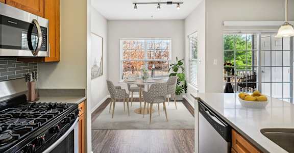A modern kitchen with a dining area in the background.