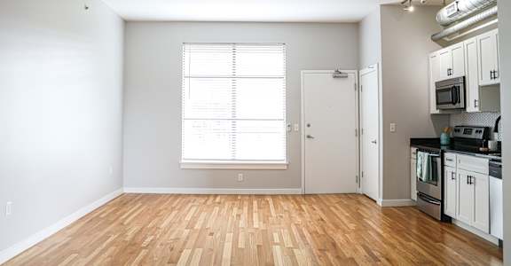 A kitchen with white cabinets and a wooden floor.