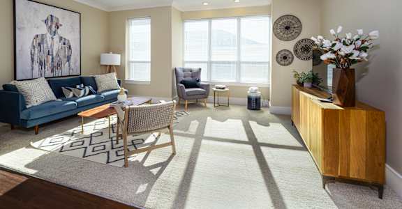 A living room with a blue couch, a wooden cabinet, and a painting on the wall.