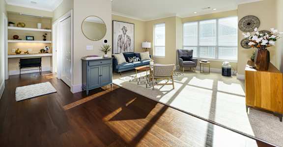 A living room with a grey couch and a wooden floor.