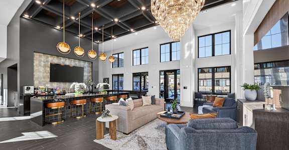 A modern living room with a bar area and a large chandelier.
