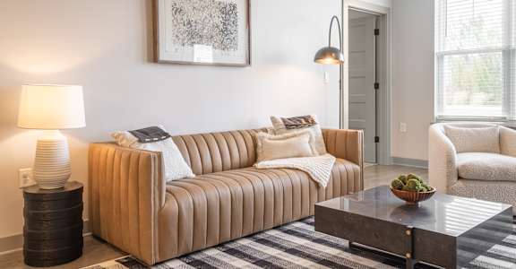 A living room with a brown couch, a coffee table, and a lamp.