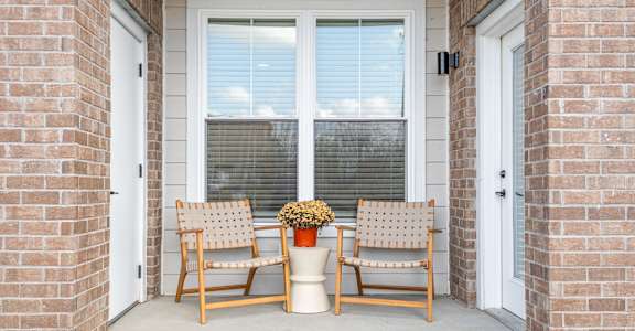 Two chairs and a planter sit on a porch.
