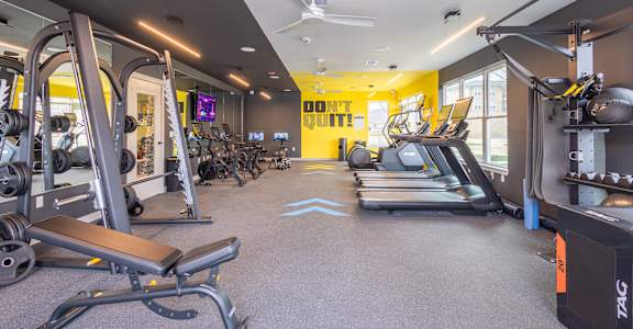 A gym with a variety of equipment including treadmills, weights, and exercise machines.