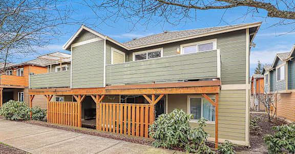 A modern house with a green siding and a wooden deck.