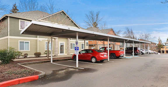 A parking lot with a building and cars parked in front.