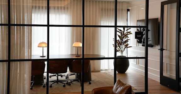 A room with a desk, chairs, and a plant.