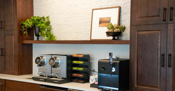 A black coffee maker is on a counter next to a black and silver toaster.