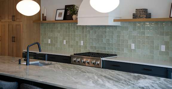 A kitchen with a marble countertop and a tile backsplash.