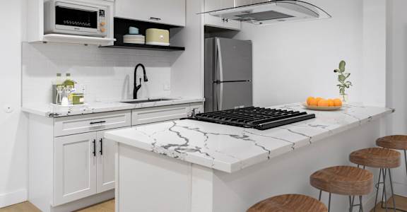 A kitchen with a black and white marble countertop and white cabinets.