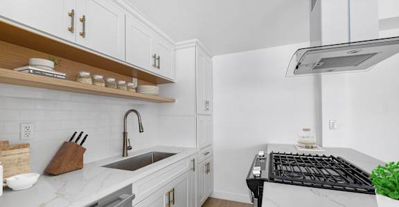 A modern kitchen with white cabinets and a black stove top.