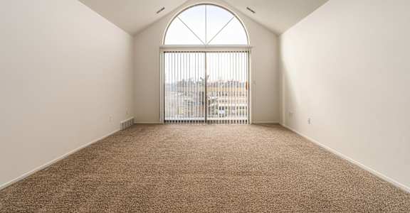 an empty living room with a large window and carpet