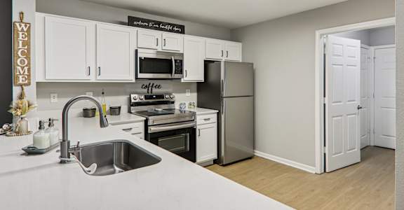 A kitchen with a sink, stove, and refrigerator.