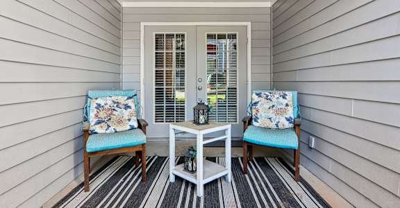 A small porch with a table and two chairs.