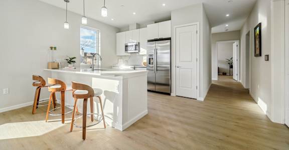 A kitchen with white cabinets and a white island with a bar stool.