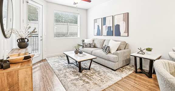 A living room with a grey couch, a coffee table, and a mirror on the wall.