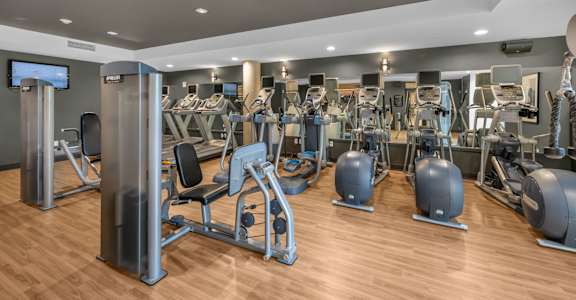 A gym with a variety of equipment including treadmills, weights, and exercise machines.