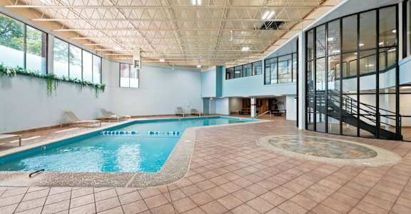 A large indoor swimming pool with a tiled floor and a glass wall.
