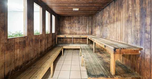 A wooden room with benches and windows.