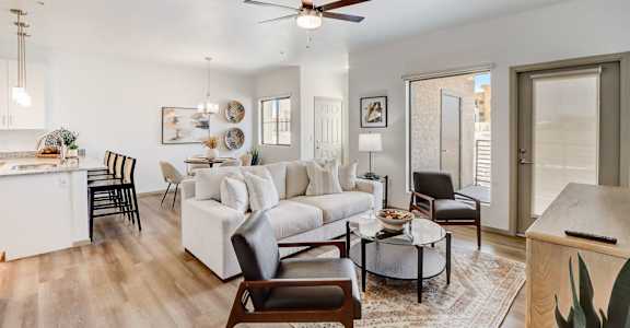 A living room with a white couch, a coffee table, and a ceiling fan.