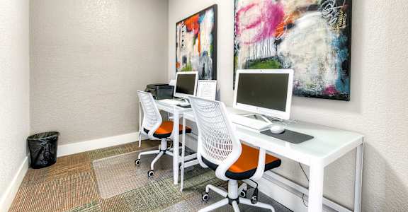 A white desk with two chairs and a computer on it.