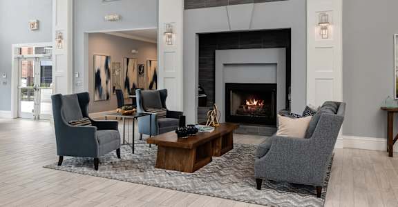 A living room with a fireplace and grey chairs.