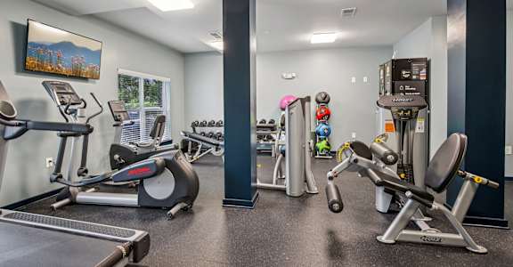 A gym with a variety of equipment including treadmills, weights, and exercise machines.