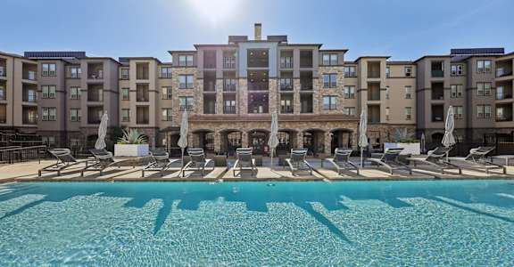 A large swimming pool in front of apartment buildings.